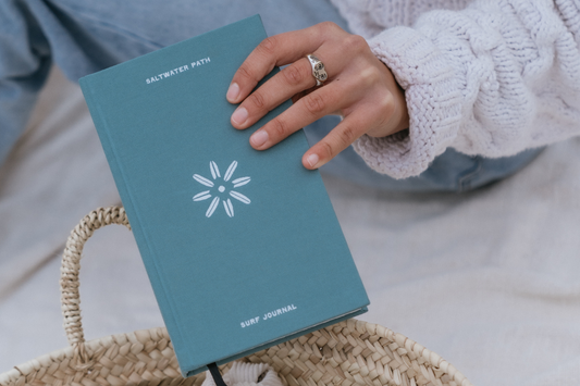 Saltwater Path surf journal being lifted out of a wicker basket on the beach